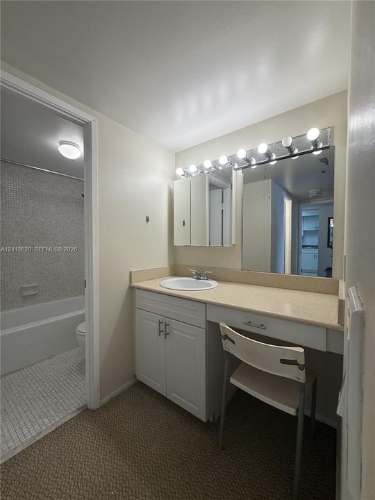 Vanity area featuring white cabinetry, an integrated surface-mount sink, an expansive countertop, a tri-fold medicine cabinet, and a multi-bulb light fixture