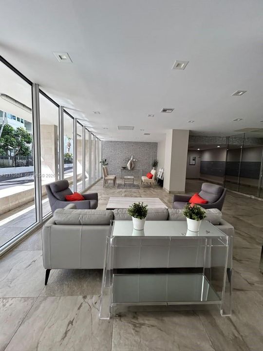 Floor-to-ceiling glass windows, recessed ceiling lighting, large-format tiled flooring, and a textured stone-finish accent wall