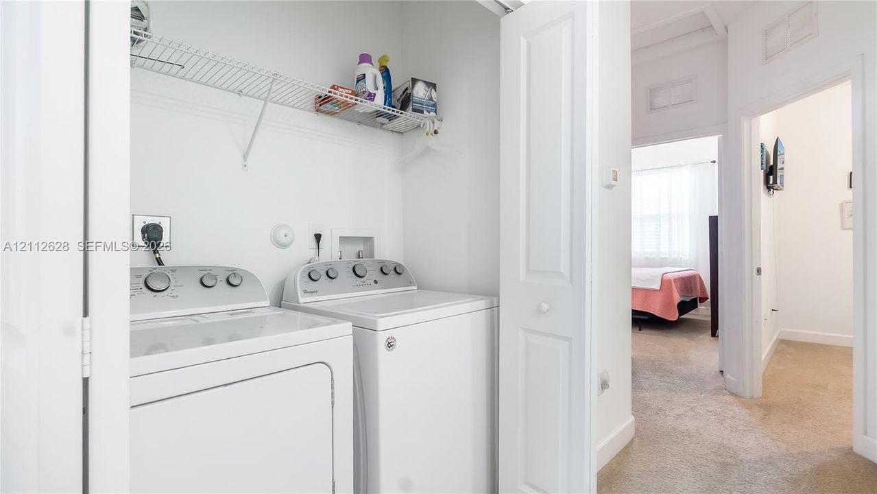 A convenient upstairs laundry closet with full-size machines and open shelving—designed to make everyday routines simple, organized, and efficient.