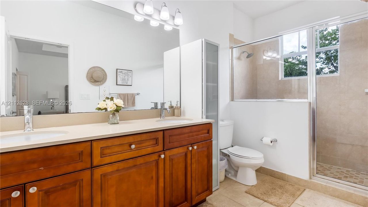 The oversized ensuite bathroom features a bright, spa-inspired walk-in shower with elegant tilework and natural light, creating a refreshing retreat to start and end your day in pure comfort.