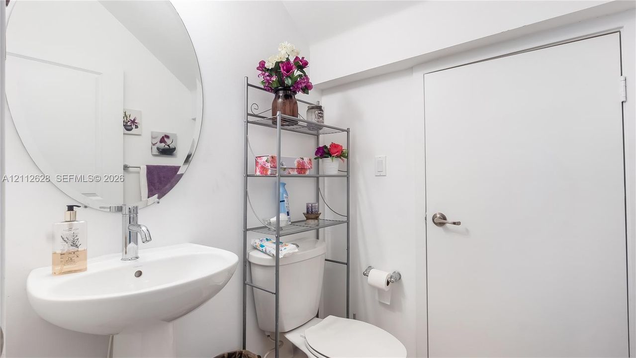A stylish powder room centrally located among all common areas, featuring a perfect storage nook for cleaning supplies and a surplus of toiletries—keeping everything organized and out of sight