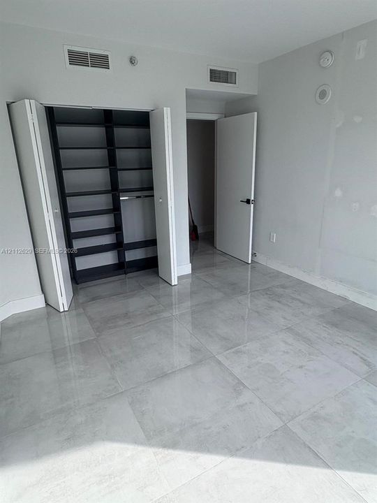 Large-format tile flooring, built-in closet shelving, and solid-core interior doors with matte black hardware