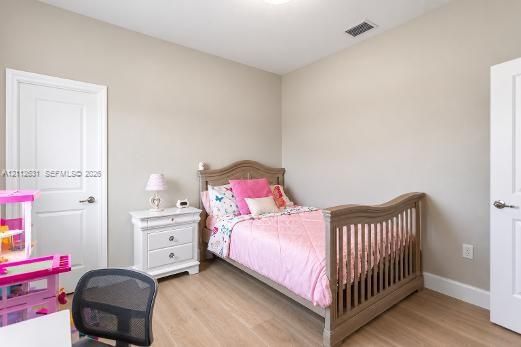 Neutral-toned interior space featuring wood-finish flooring, two white paneled doors, and a ceiling-mounted light fixture