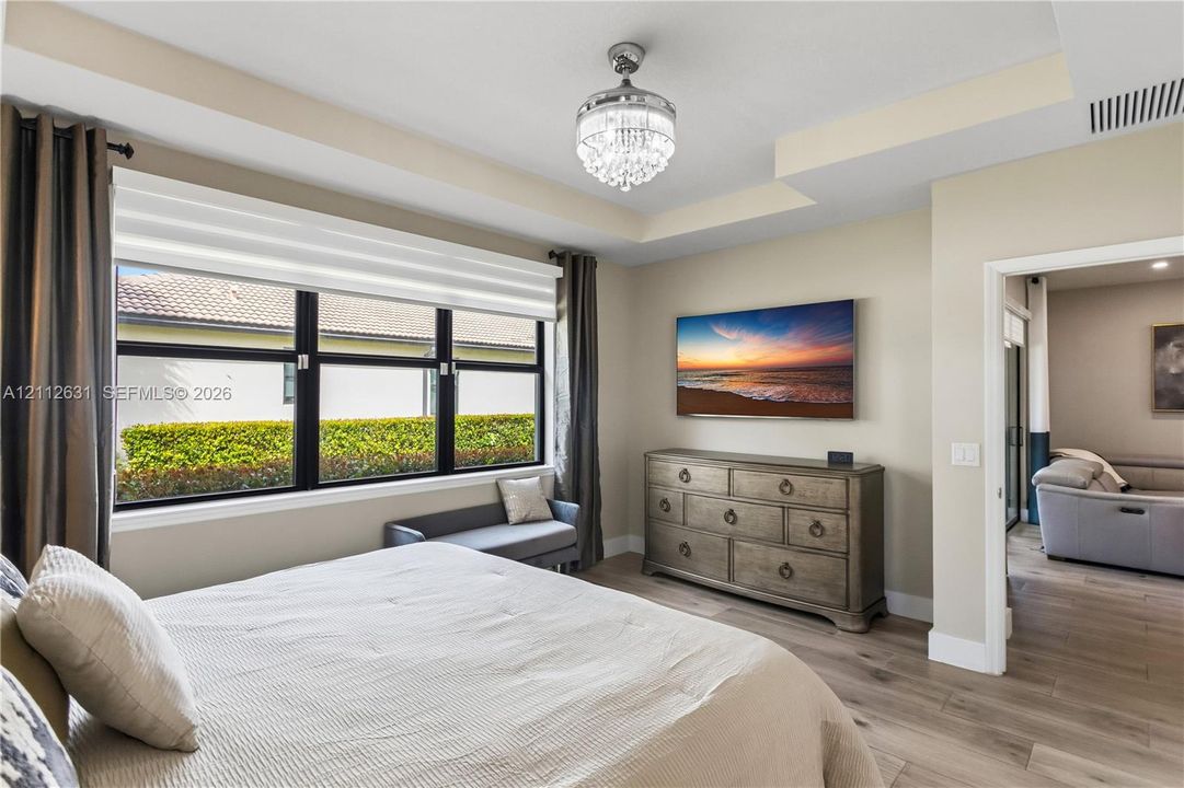Tray ceiling featuring a crystal chandelier, wood-finish flooring, and large windows with black frames