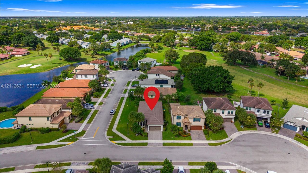 Aerial perspective of a single-family residence featuring a paved driveway, attached multi-car garage, and a hip roof, situated on a residential cul-de-sac