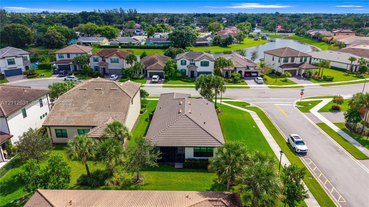 Aerial perspective of a single-story residence featuring a hipped tile roof, concrete driveway, attached multi-car garage, and manicured landscaping