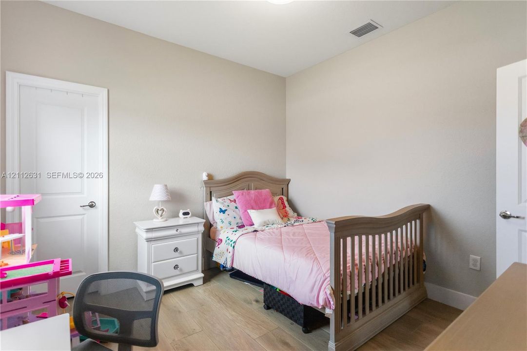 Room with wood-finish flooring, neutral wall paint, and two interior doors with brushed nickel hardware