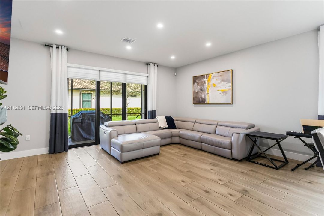 Living area featuring wood-finish flooring, recessed lighting, and large sliding glass doors with black framing