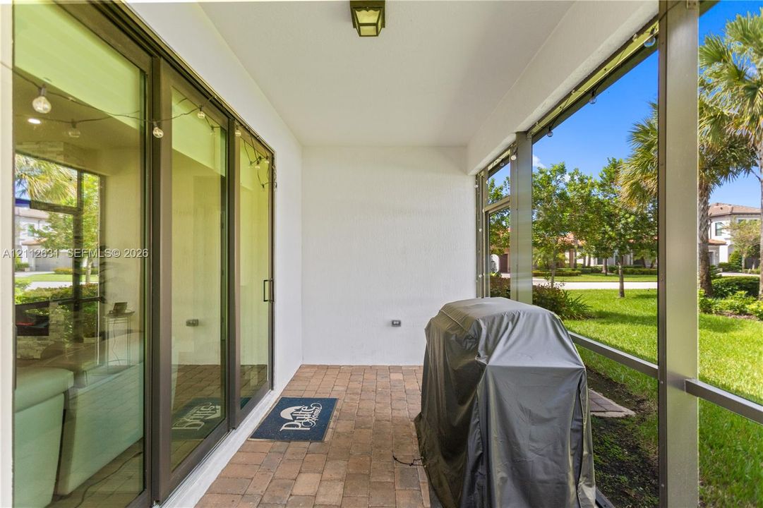 Screened-in lanai featuring paver flooring, overhead lighting, and floor-to-ceiling glass sliding doors