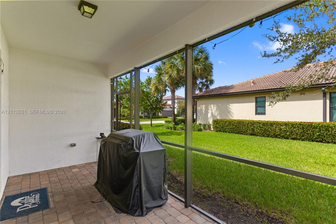 Screen-enclosed covered patio featuring paver flooring, stucco walls, and an exterior light fixture