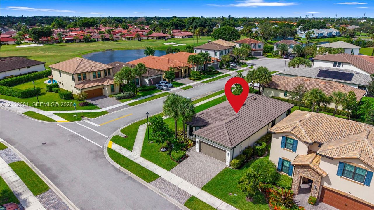 Aerial view of a residential property featuring a tiled roof, paver driveway, and an attached two-car garage