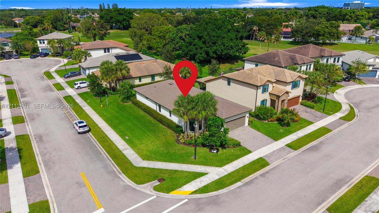 Corner lot property featuring a multi-hipped tile roof, concrete driveway, attached garage, and manicured landscaping