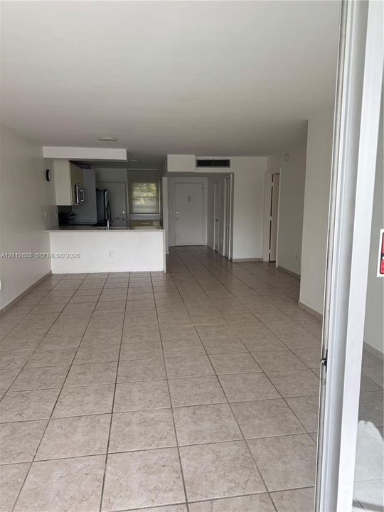 Open-concept interior featuring large-format ceramic tile flooring, neutral wall finishes, and a breakfast bar peninsula