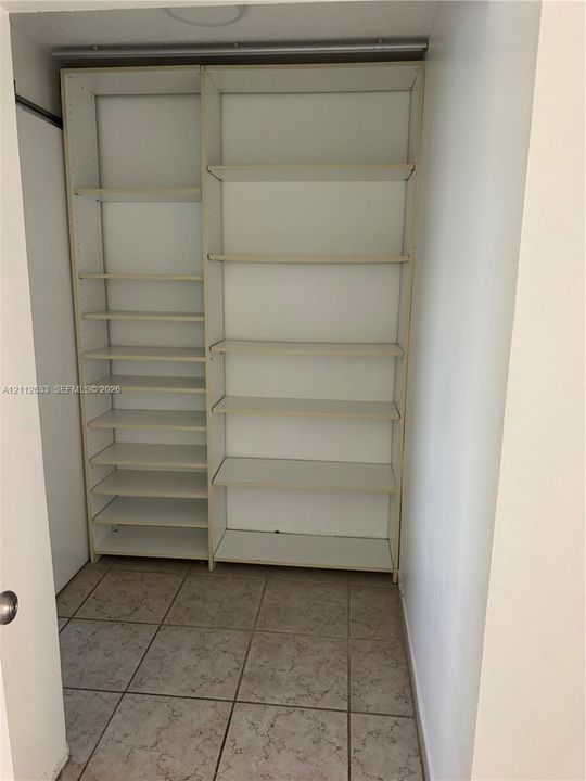 Built-in white storage shelving featuring adjustable shelving units and tiled flooring