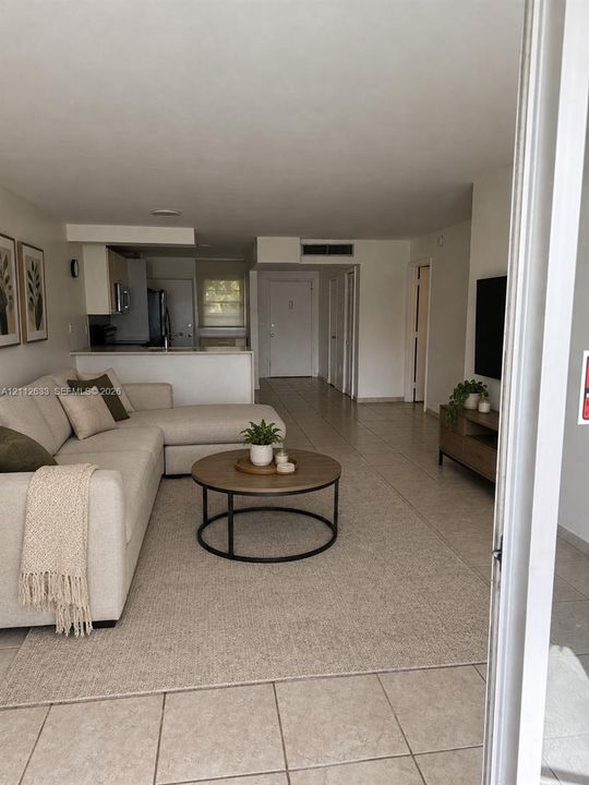 Open-concept floor plan featuring tile flooring, neutral wall tones, and a kitchen breakfast bar
