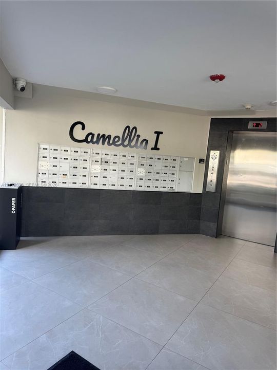 Lobby featuring large-format ceramic floor tiling, stainless steel elevator, integrated mailbox bank, and decorative stone wall cladding