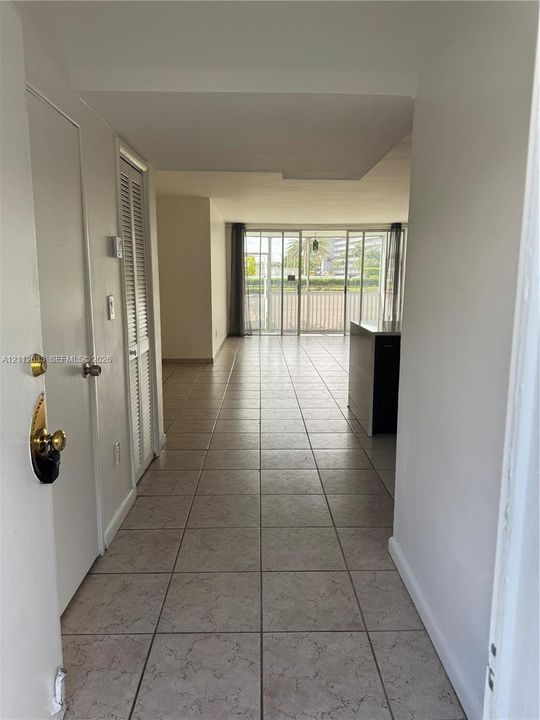 Ceramic tile flooring, louvered bi-fold closet doors, and floor-to-ceiling glass sliding doors opening to a balcony