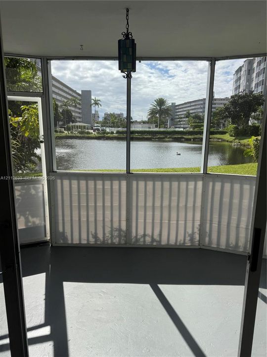 Screened-in enclosure featuring a hanging lantern-style light fixture, concrete flooring, and water frontage