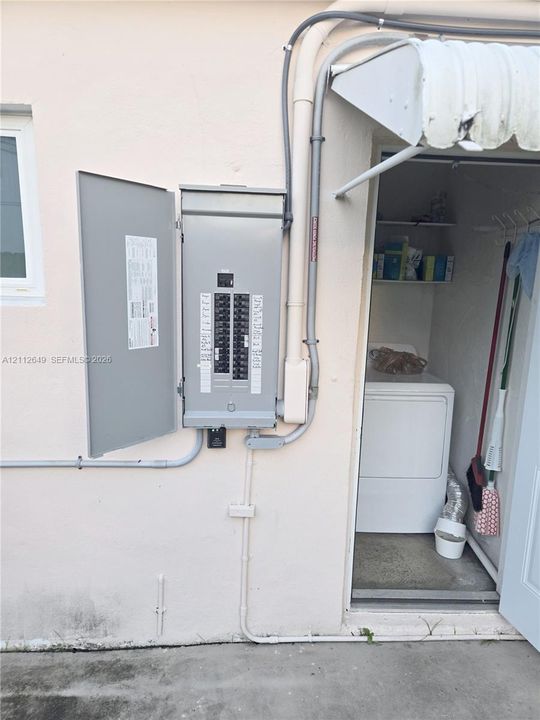 Electrical panel with a multi-circuit breaker configuration mounted to the exterior wall, featuring metal conduit and a metal awning overhead