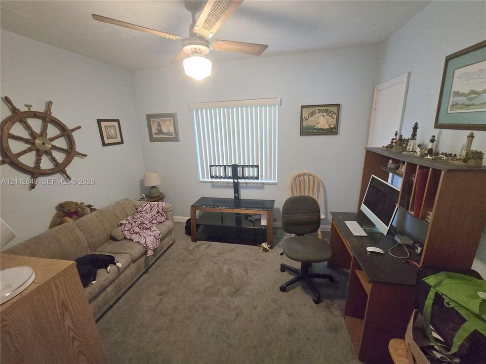 Carpeted room featuring a ceiling fan with integrated light fixture and vertical slat window blinds