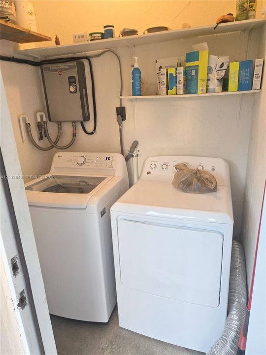 Laundry area featuring wall-mounted shelving and a tankless water heater