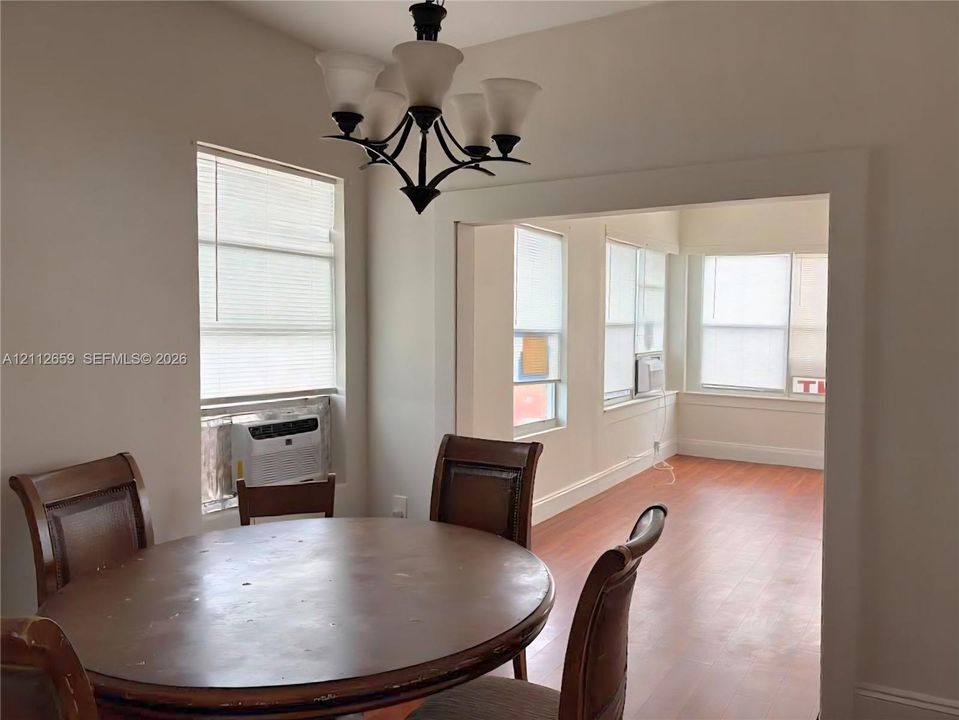 Wood-finish flooring, multi-light metal chandelier, and white wall trim accents