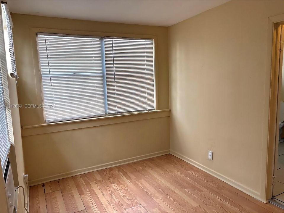 Wood-finish flooring, neutral wall tones, and horizontal window blinds featuring a window sill and chair rail