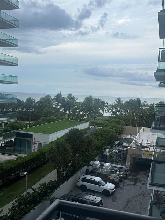 Balcony featuring glass railings and an expansive horizon line including ocean and coastal greenery