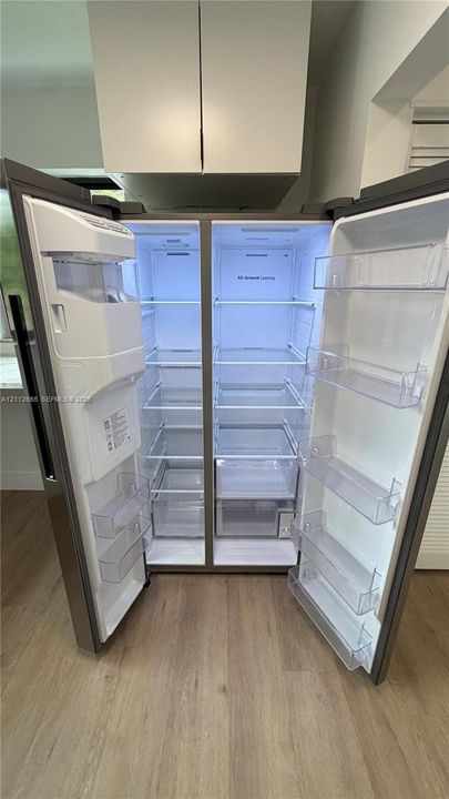 Stainless steel side-by-side refrigerator featuring adjustable glass shelving, clear storage drawers, integrated door shelving, and an in-door water and ice dispensing system