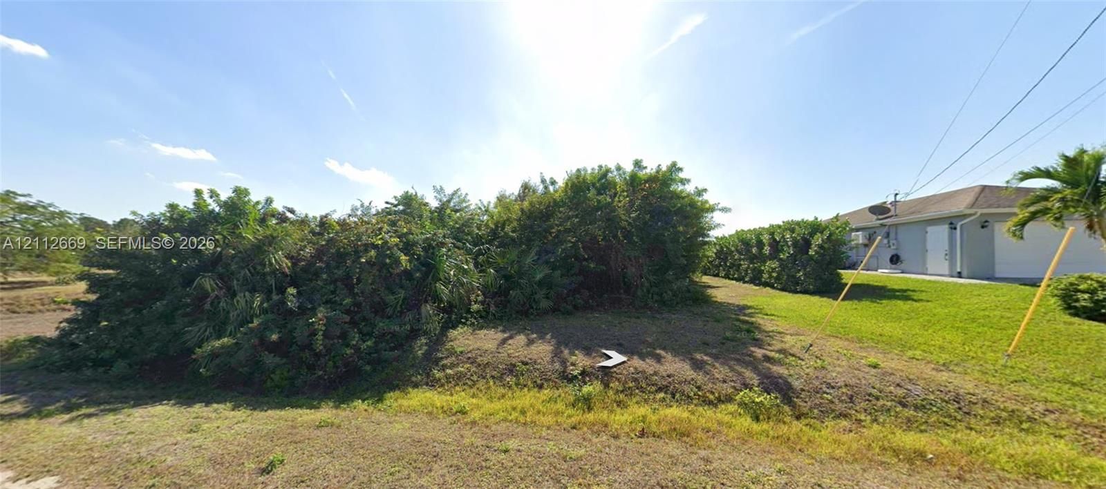 Expansive lot featuring mature landscape hedging, open grass areas, and established tropical vegetation