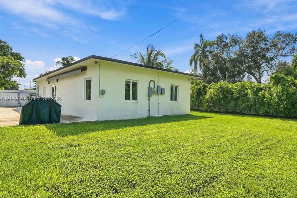 Exterior featuring a smooth-finish stucco facade, flat roofline, and expansive manicured lawn