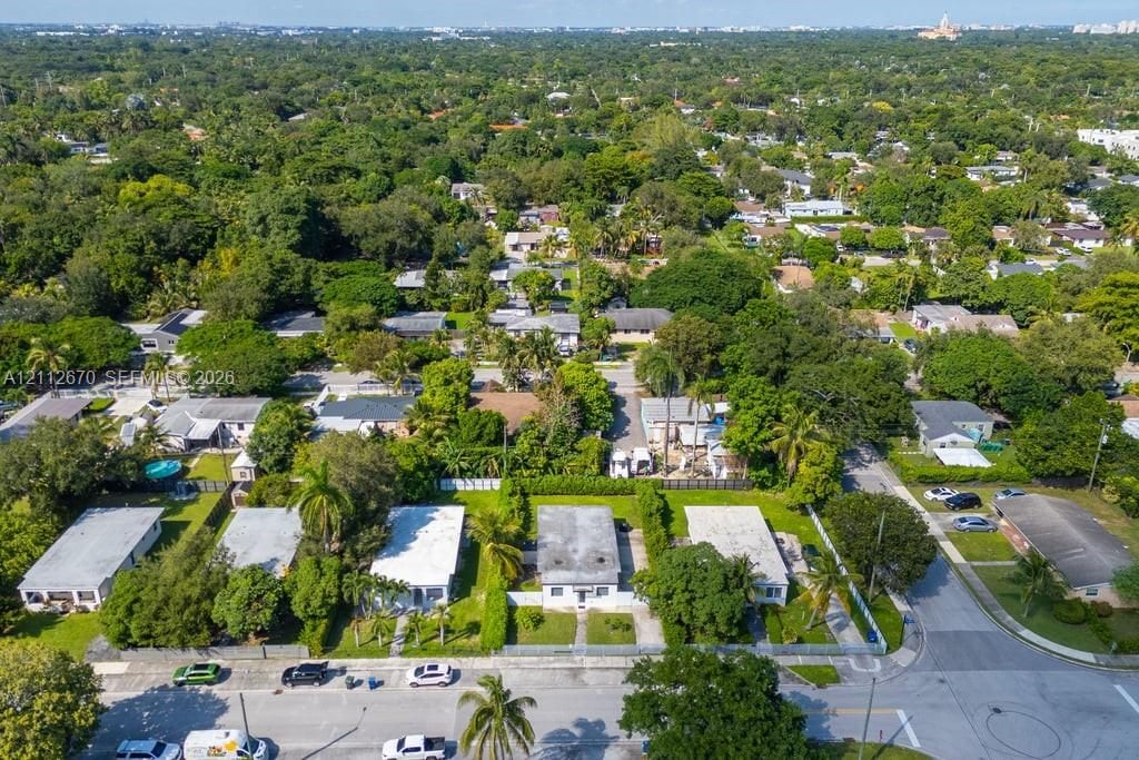 Aerial perspective of a residential neighborhood featuring established tree canopy, paved street grids, and singular detached structures on landscaped lots