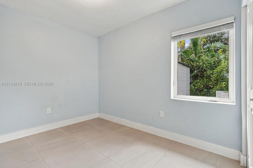Neutral-toned walls paired with large-format tile flooring and a single-pane window featuring horizontal blinds