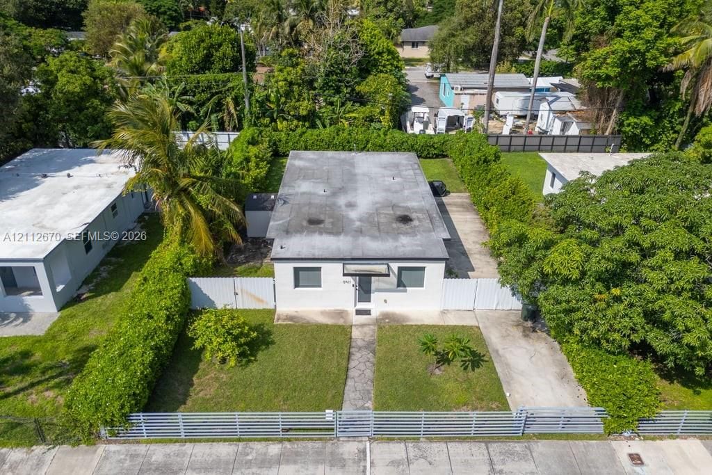 Detached structure featuring a flat roof, white exterior siding, concrete driveway, and a fenced perimeter