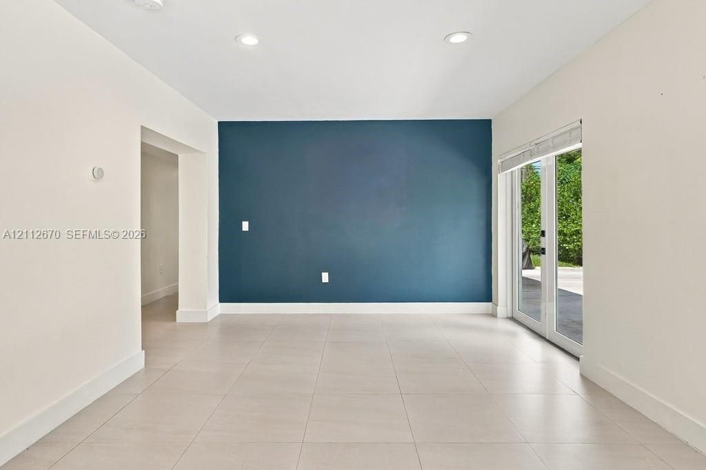 Interior space featuring large-format tile flooring, recessed ceiling lighting, a dark blue accent wall, and double glass doors