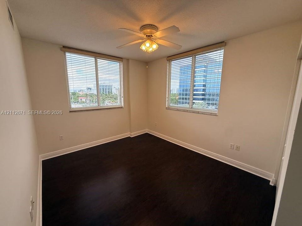 Room featuring wood-finish flooring, dual windows with integrated blinds, and a centrally mounted ceiling fan with light fixture