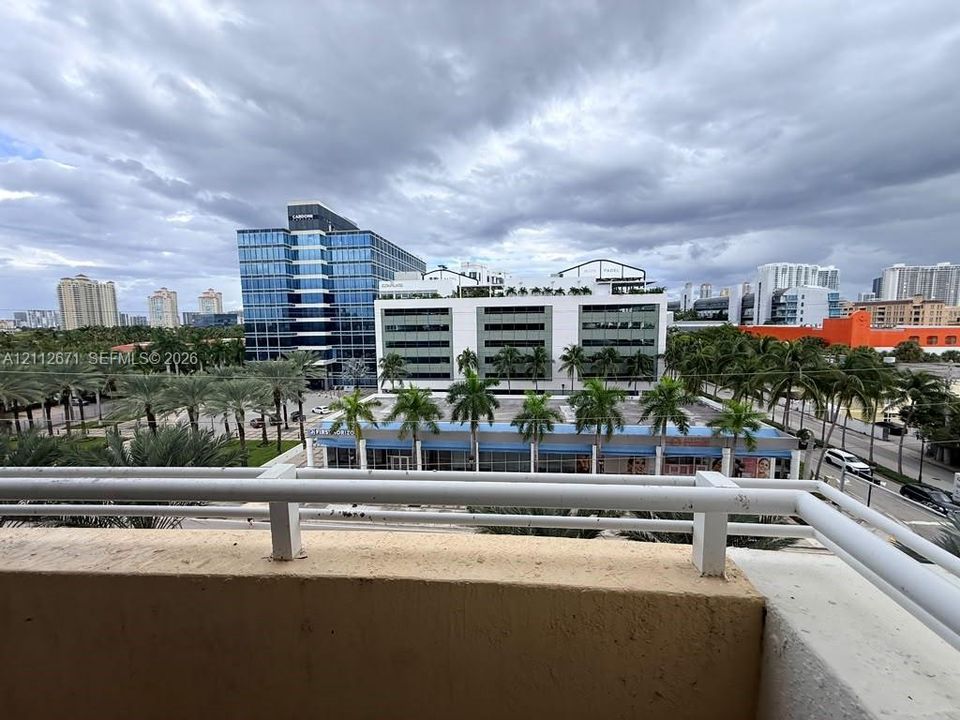 Outdoor balcony with white metal railings featuring an urban skyline backdrop