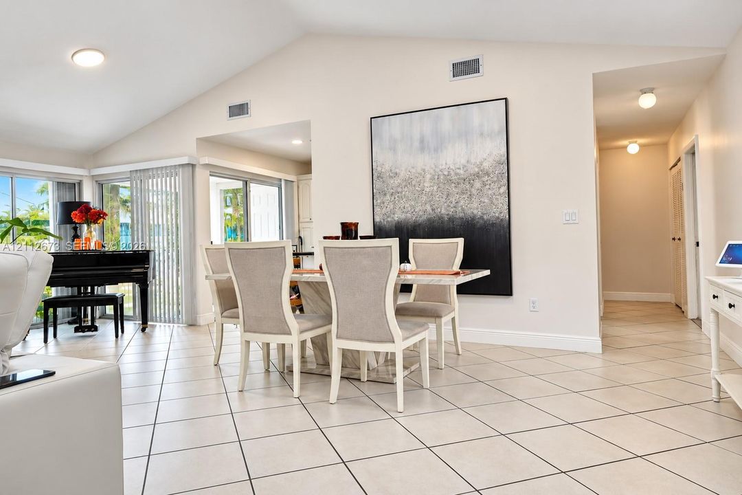 Vaulted ceilings, large-format diagonal tile flooring, and multiple sliding glass doors featuring vertical blinds