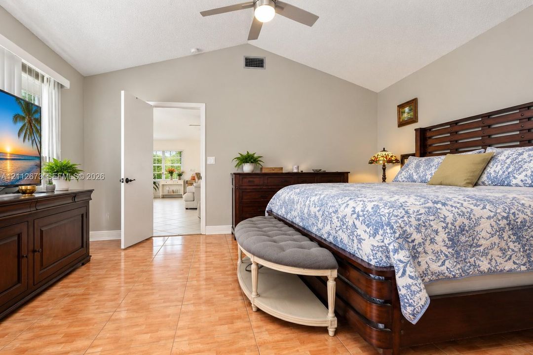 Vaulted ceiling featuring a central brushed-nickel finish ceiling fan and ceramic tile flooring