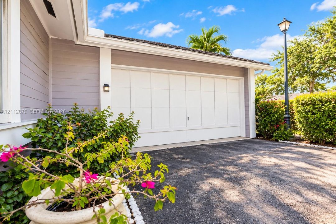 Exterior featuring horizontal siding, multi-panel garage door, attached wall-mounted light fixture, and paved driveway