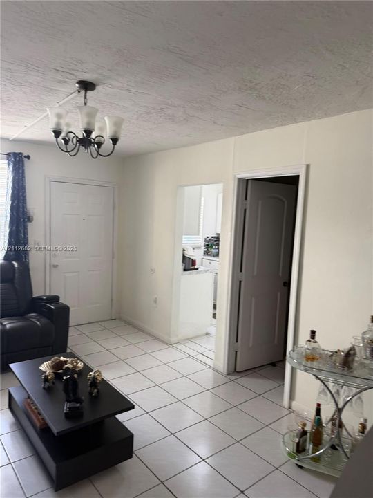 Interior featuring large-format ceramic tile flooring, five-light iron chandelier, and neutral wall tones