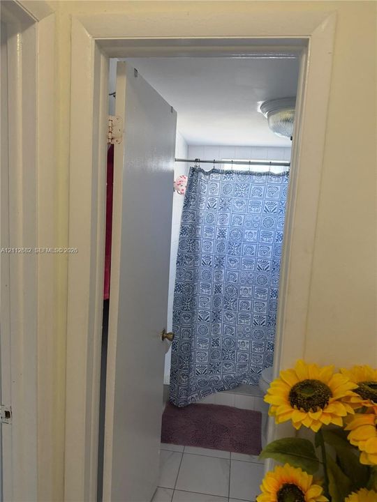 Enclosed room featuring a neutral-toned door, white-framed doorway, and tile flooring