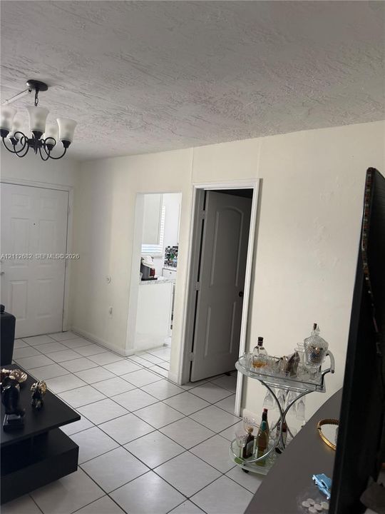 Interior space featuring tile flooring, six-panel interior doors, and a decorative multi-arm chandelier