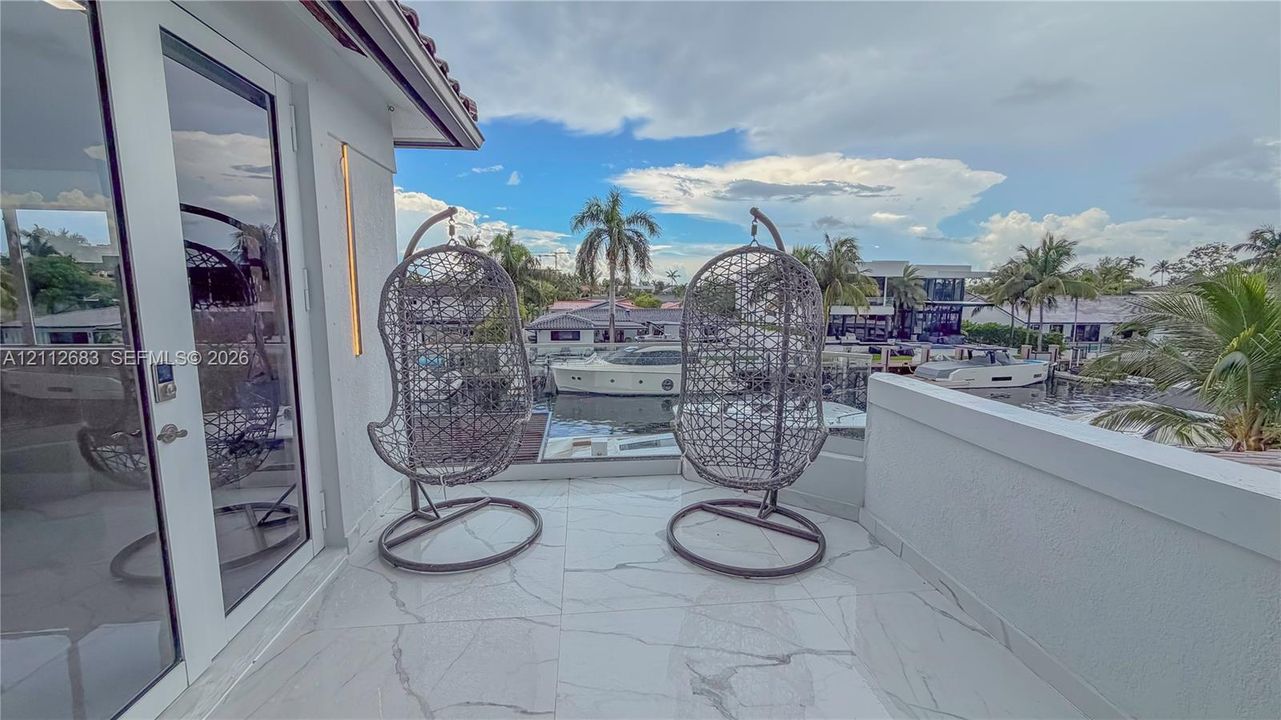 Balcony featuring large-format tile flooring, glass-paneled double doors, and a solid perimeter wall overlooking a canal and boat dock