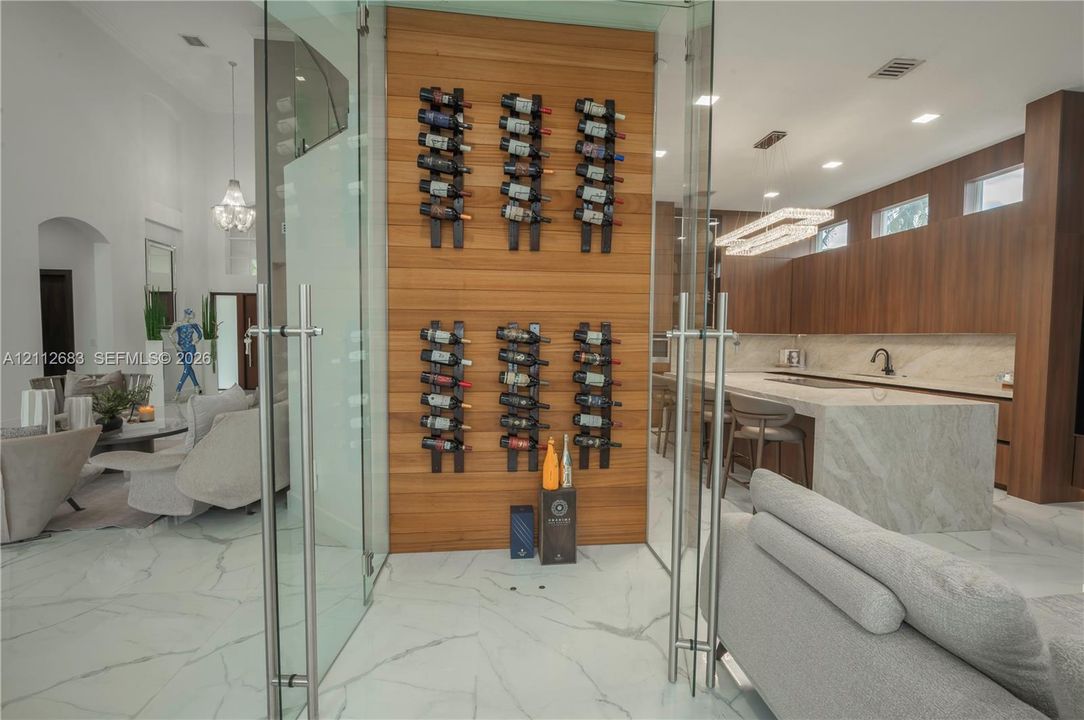 Glass-enclosed wine storage featuring a vertical wood-plank accent wall and wall-mounted bottle racks, set within a space showcasing large-format stone flooring and recessed lighting