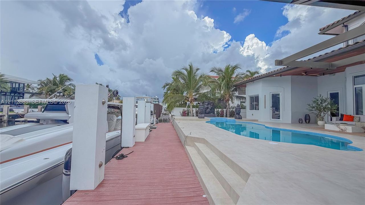 Waterfront property featuring a private boat dock, a concrete pool deck, and a custom-shaped swimming pool