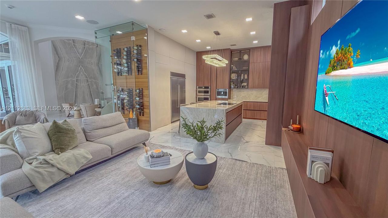 Modern interior featuring a custom glass-enclosed wine display, large-format stone flooring, wood-finish cabinetry, a waterfall-edge kitchen island, and recessed lighting