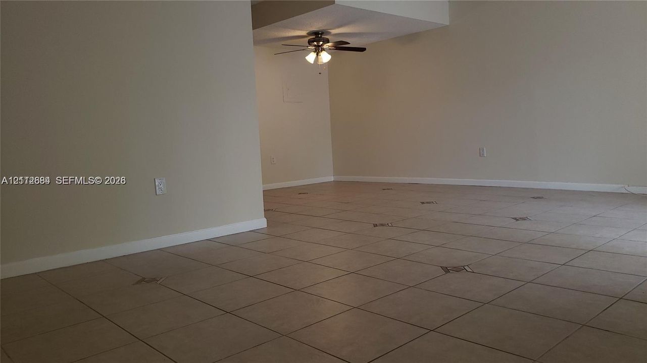 Neutral-toned interior space featuring large-format tile flooring with decorative inlay accents and a ceiling fan with integrated light fixture