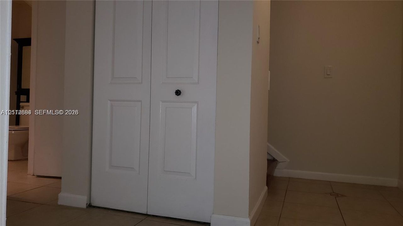 Double-door closet with recessed paneling and a dark circular knob, complemented by neutral tile flooring