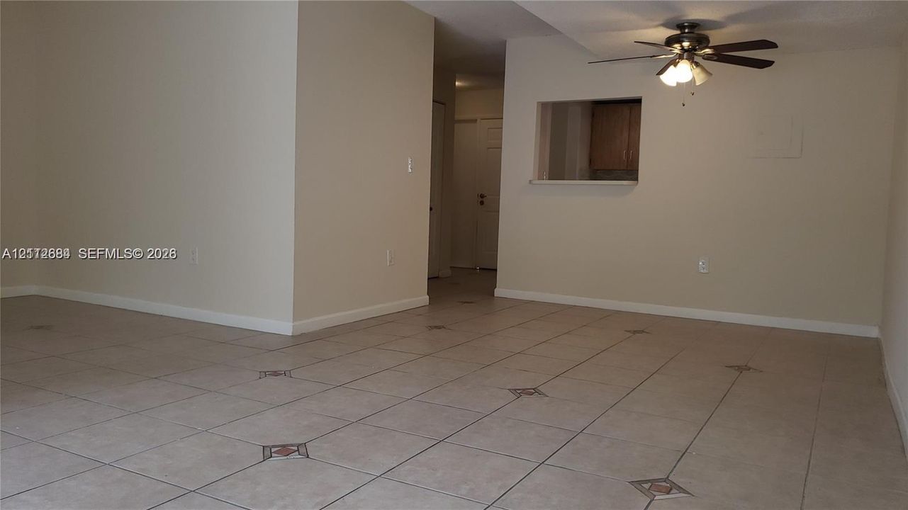 Interior space featuring neutral wall paint, ceramic tile flooring with decorative inserts, and a ceiling fan with integrated lighting